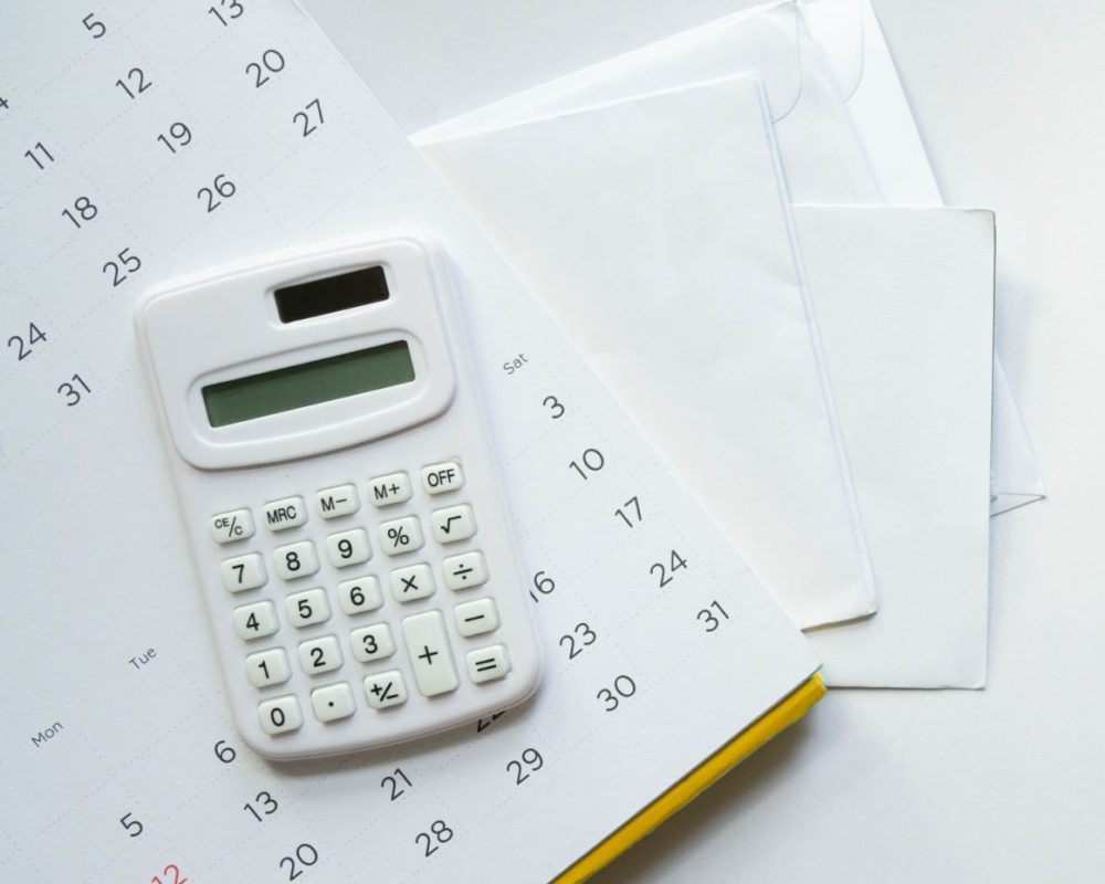 Calculator and envelopes on a calendar.