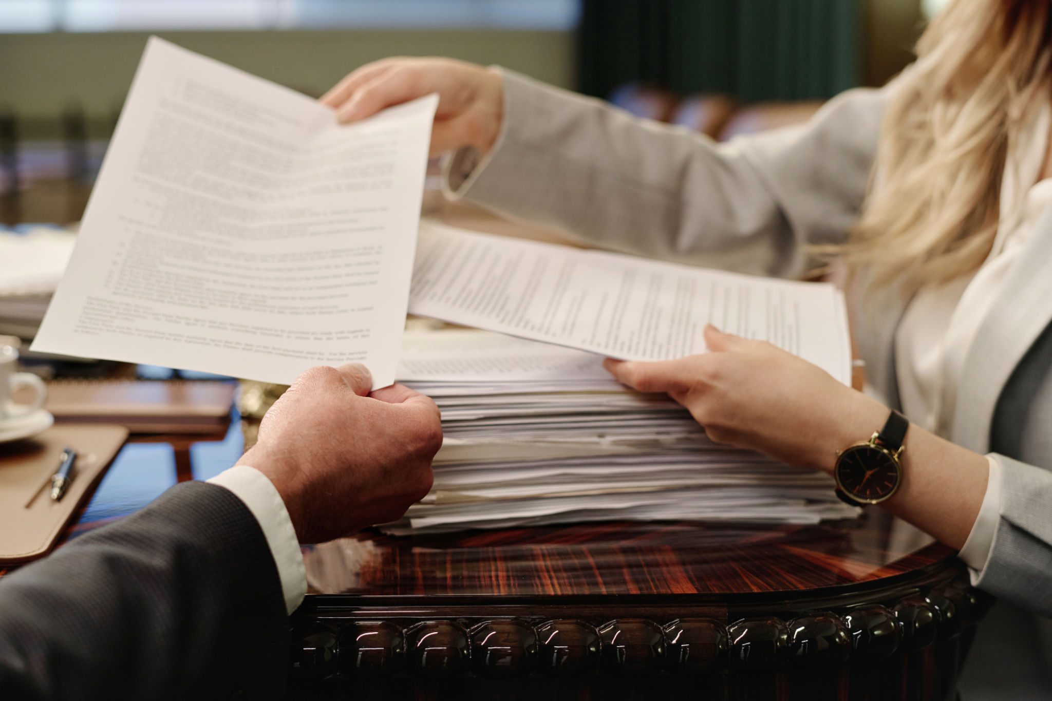 Hands exchanging documents over desk.